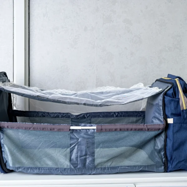 Foldable 2-in-1 diaper backpack opened into a portable baby bed with mesh sides, adjustable canopy support, and multiple storage compartments.