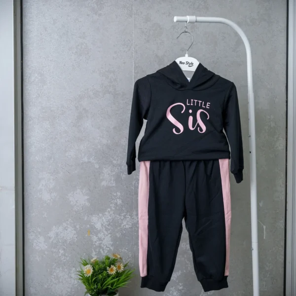 Black and pink "Little Sis" 2 pcs Outfit featuring a hooded sweatshirt with pink lettering and matching jogger pants with pink side stripes, displayed on a hanger.