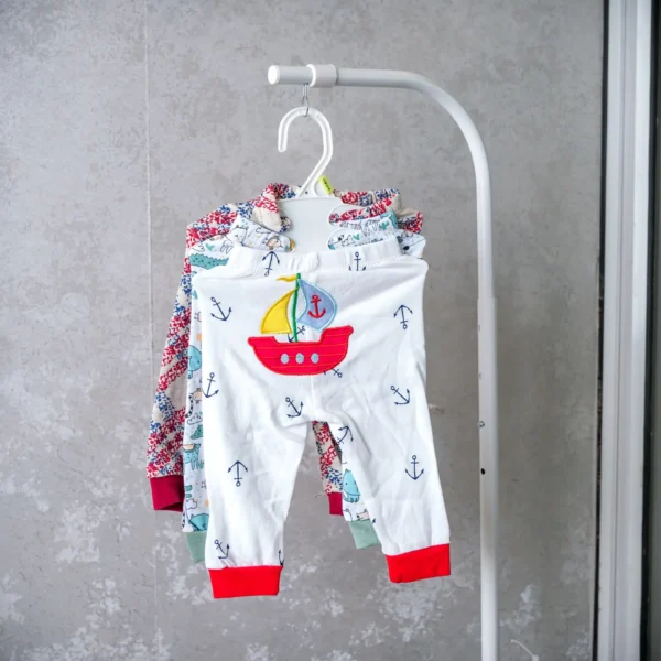 Pack of baby trousers including white pants with a red and yellow sailboat patch, accented with nautical anchor prints.