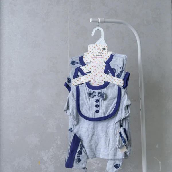8-piece neutral baby receiving set in grey with navy blue bowtie print, featuring formal-style bib, bodysuit, and matching accessories.