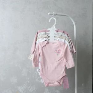 A collection of baby bodysuits on a hanger, with the front one in bright red featuring ladybugs and the text “mommy & me.