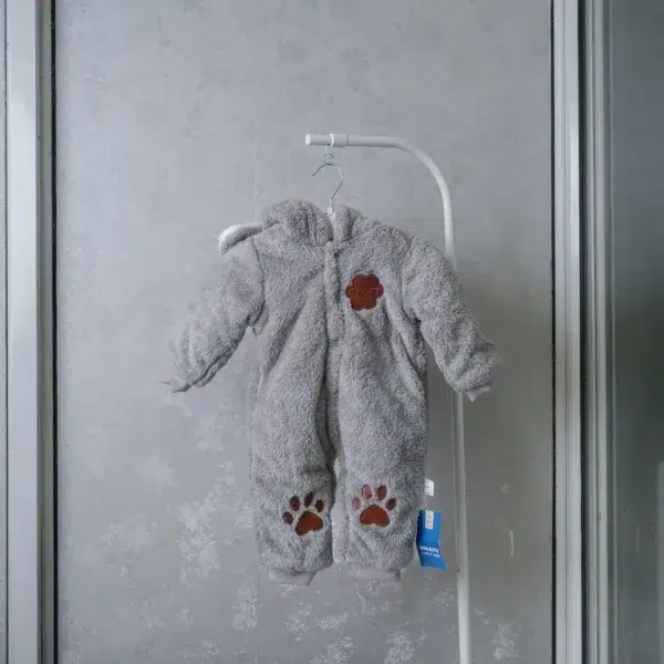 fleece baby romper with hood and animal ears, featuring paw print knee accents, front zipper, and snap-button leg openings, displayed on a flat surface.
