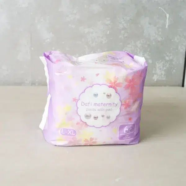 A single pack of "Dafi Maternity Pants with Pad" in size L-XL with a floral-themed purple and pink design, labeled as containing 6 pieces for postpartum comfort and protection.