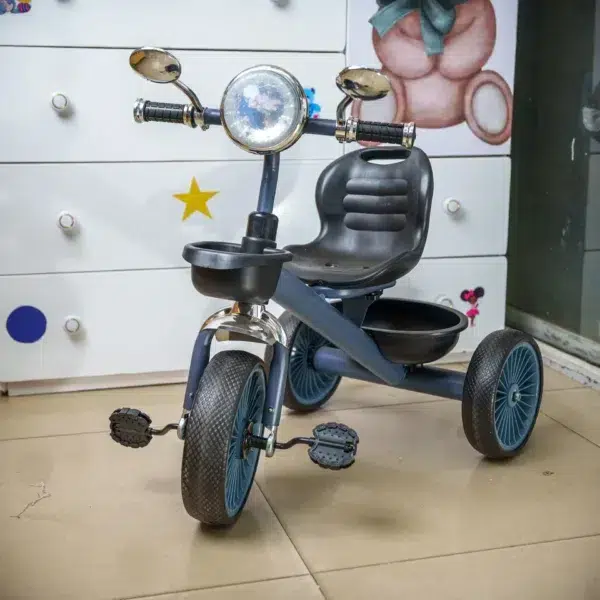 hildren’s tricycle with a black seat, blue wheels, and handlebar mirrors, displayed indoors on a tiled floor near a white dresser with colorful decor.