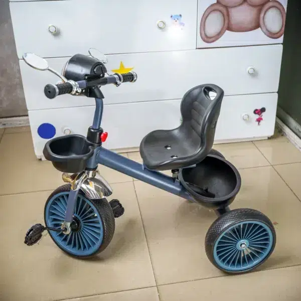 hildren’s tricycle with a black seat, blue wheels, and handlebar mirrors, displayed indoors on a tiled floor near a white dresser with colorful decor.
