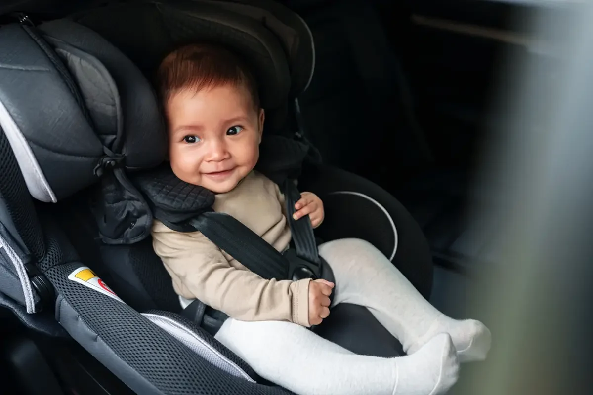 A happy baby securely strapped in a child safety seat, ensuring maximum safety and comfort while traveling.